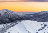 Neal Pritchard: An aerial view of the Snowy Mountains in Country Victoria with an orange lit sky